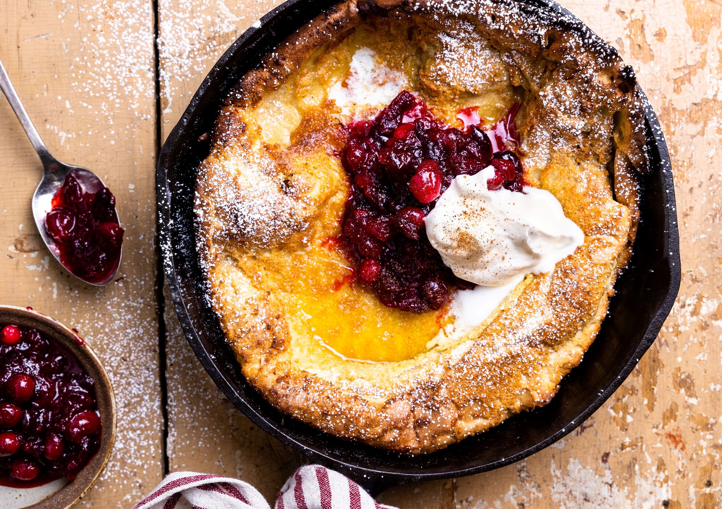 spiced cranberry dutch baby served in a cast iron pan